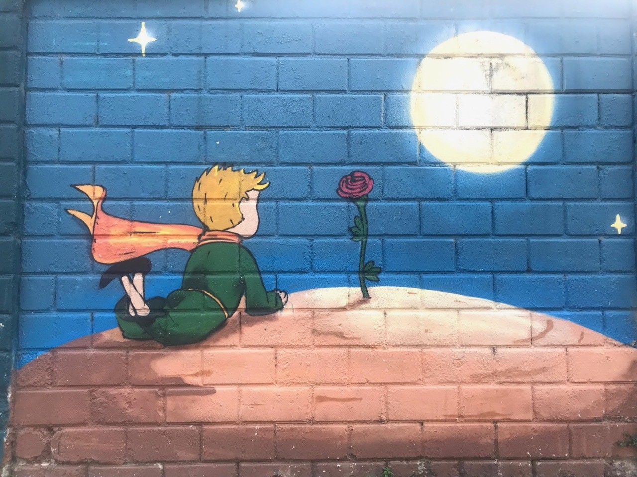 Street Art of young boy watching rose in the moonlight in Isola