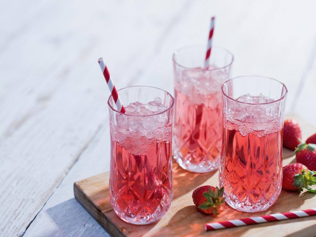 strawberry bellinis on a board with red straws