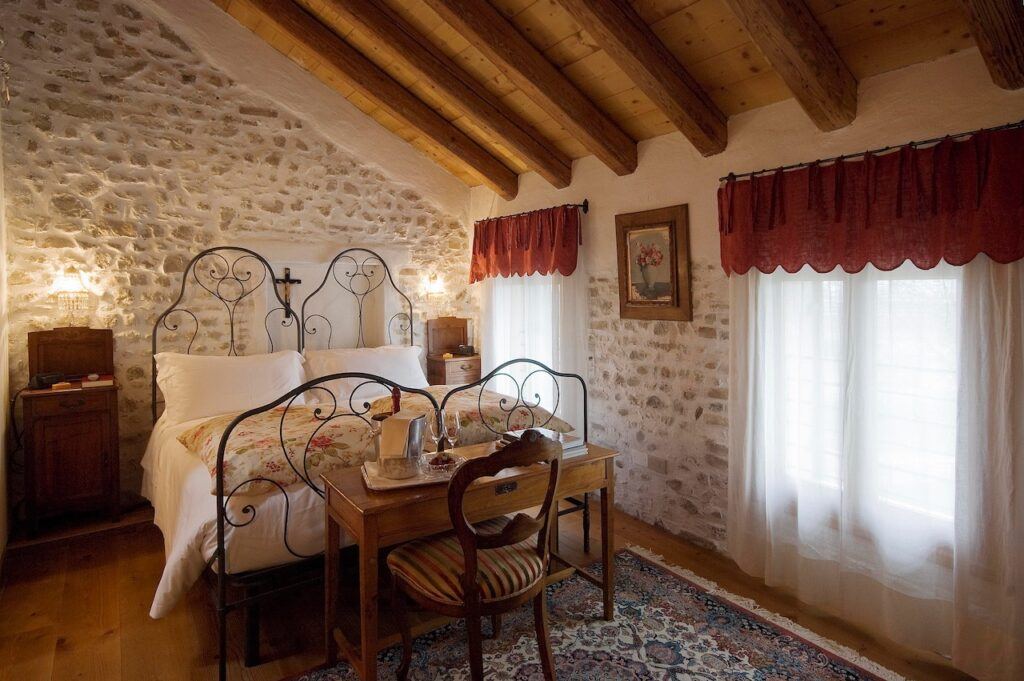 bed with white drape curtains in wood beamed room