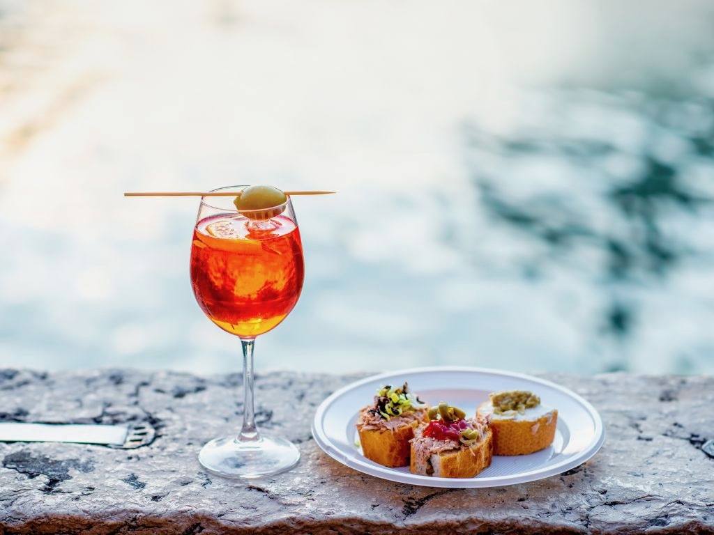 aperol spritz with plate of appetizers near canal in venice