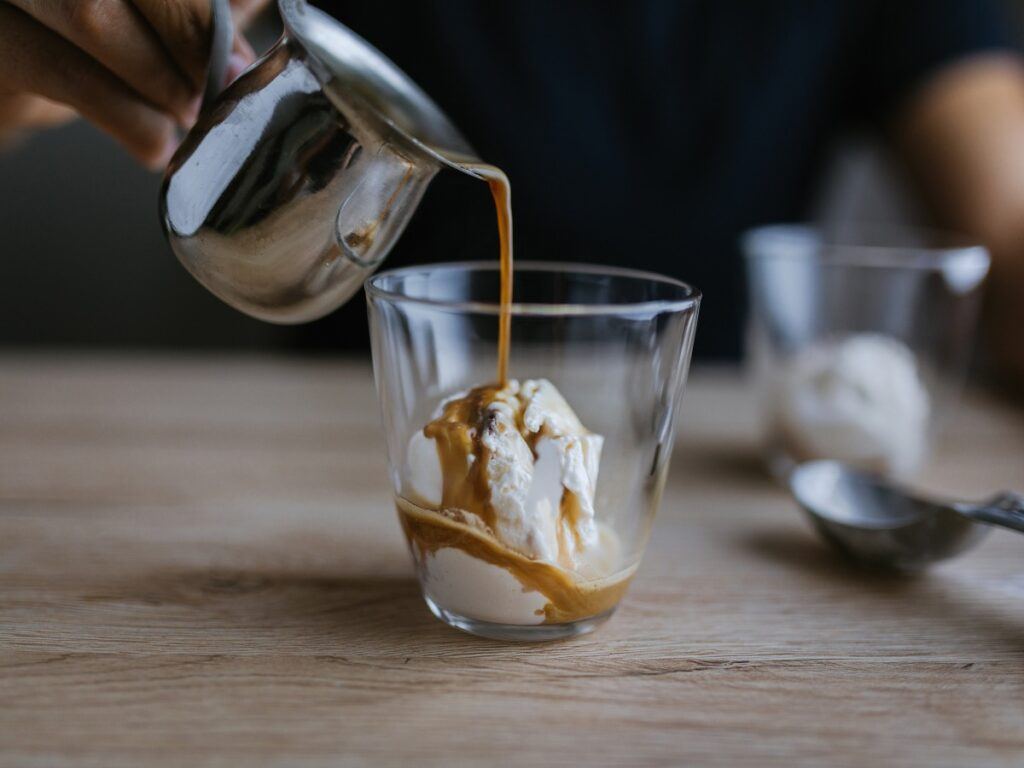 coffee poured over ice cream in glass to make affogato