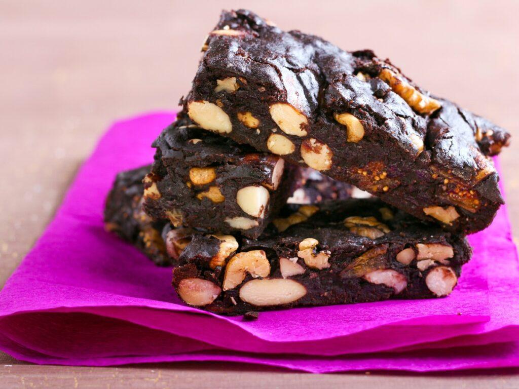 Dark sticky cake with nuts and fruit on bright pink napkin