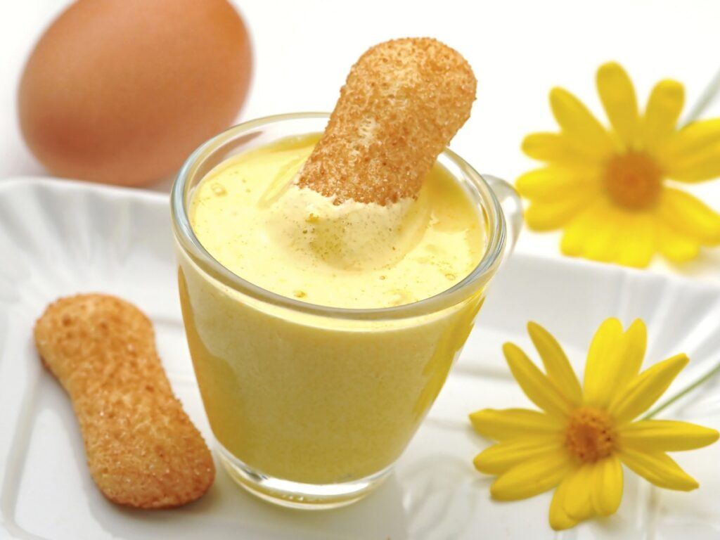 Creamy yellow zabaglione with biscuit dunked in. Yellow flour and egg background decoration