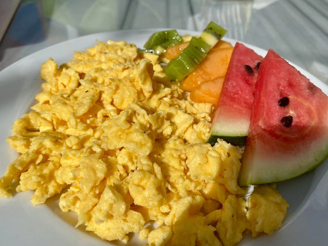 Plate of scrambled eggs with side of fruit